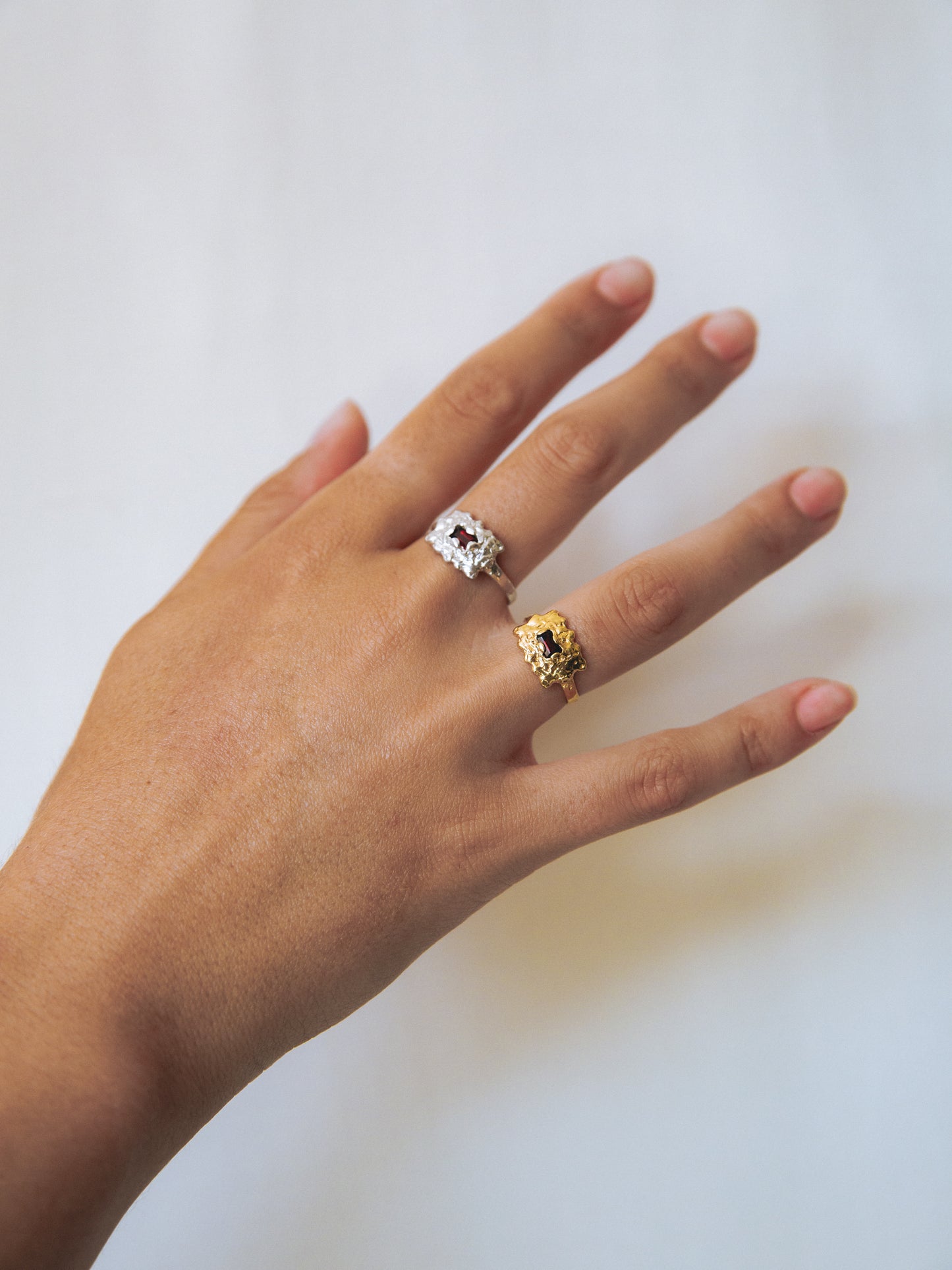 Hand wearing two rings on a plain background