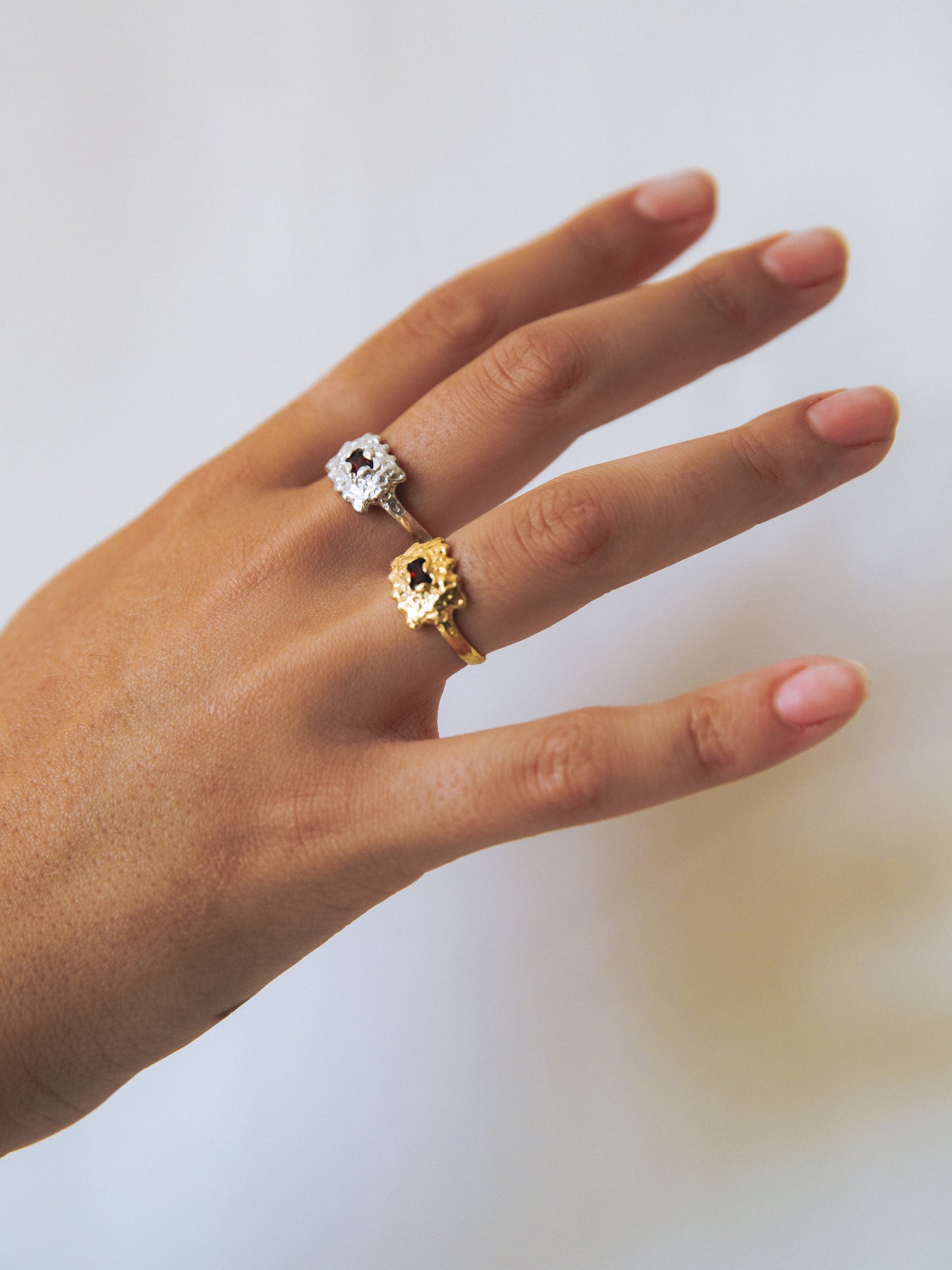 Hand wearing two rings with a plain background