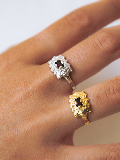 Close-up of a hand wearing two decorative rings on a neutral background