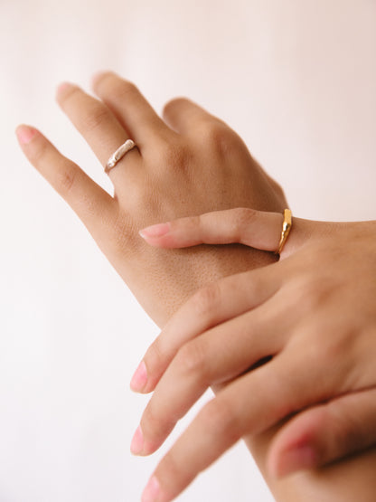 Close-up of two hands with gold rings on a light background