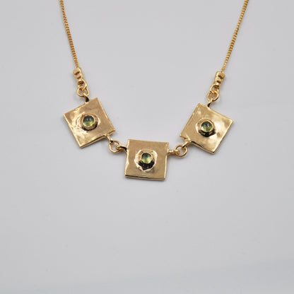 Gold necklace with square pendants on a light gray background