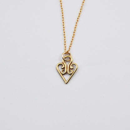 Gold heart-shaped pendant necklace on a light gray background