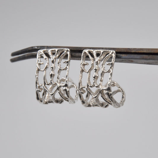Silver intricate designed earrings on a gray background