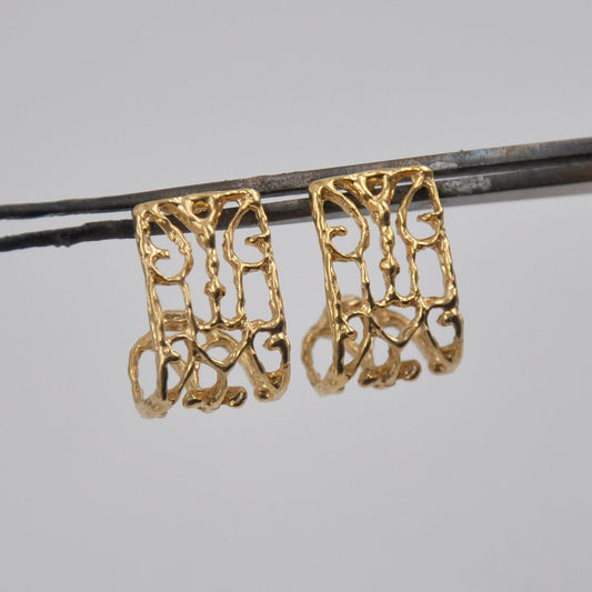 gold intricate designed earrings on a gray background