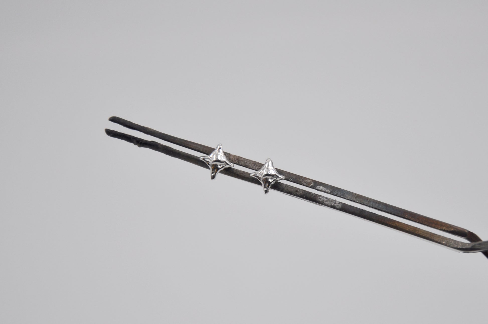 Silver star shaped stud earrings on a gray background