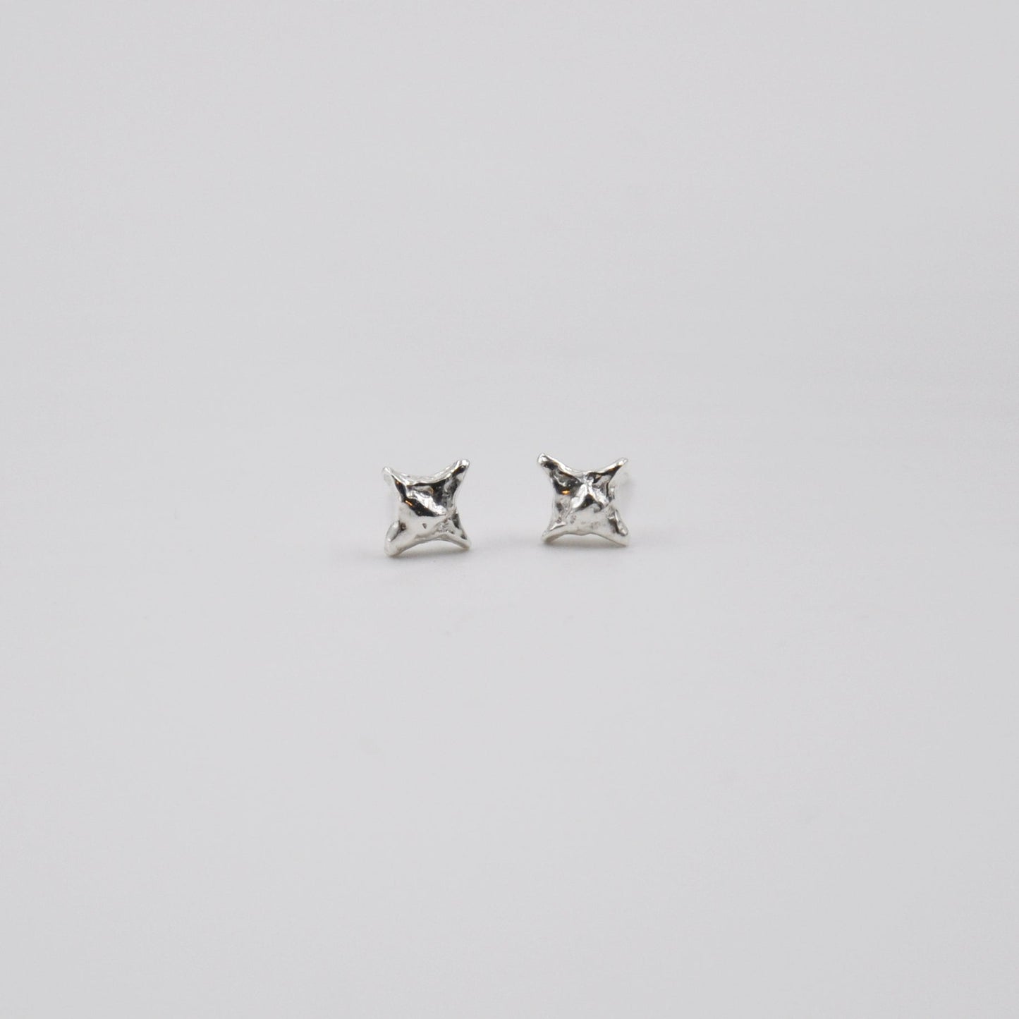 Pair of silver star stud earrings on a light gray background
