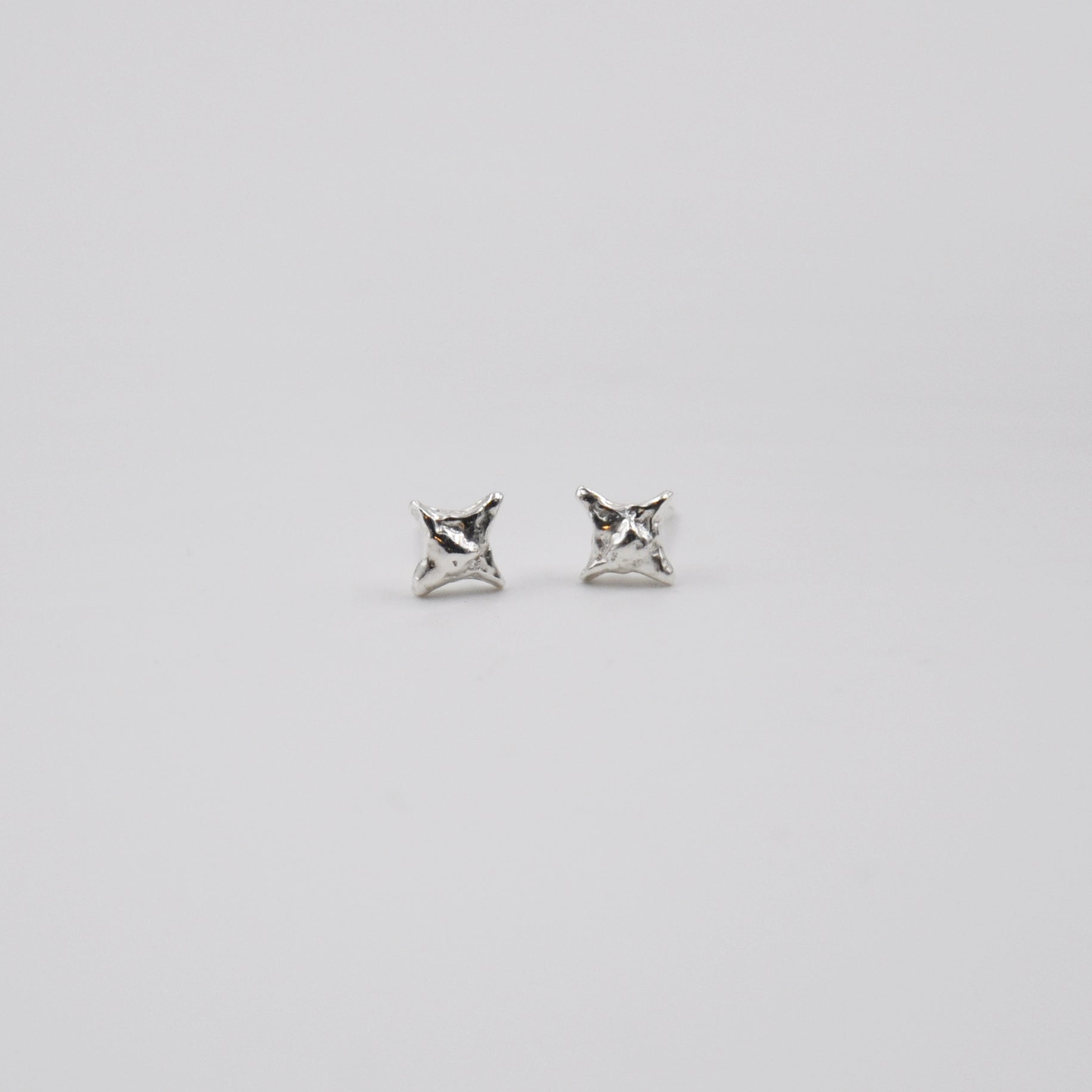 Pair of silver star stud earrings on a light gray background