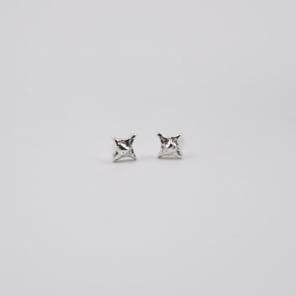 Pair of silver star stud earrings on a light gray background