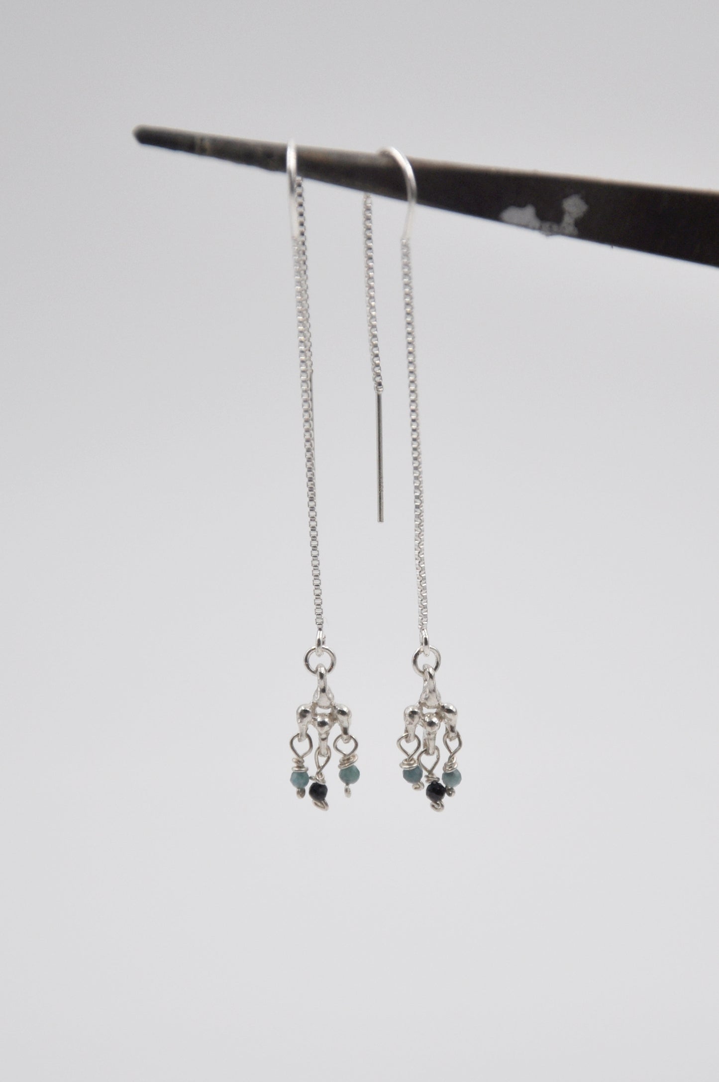Silver earrings with beads on a gray background