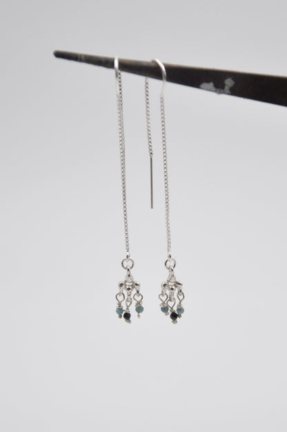 Silver earrings with beads on a gray background