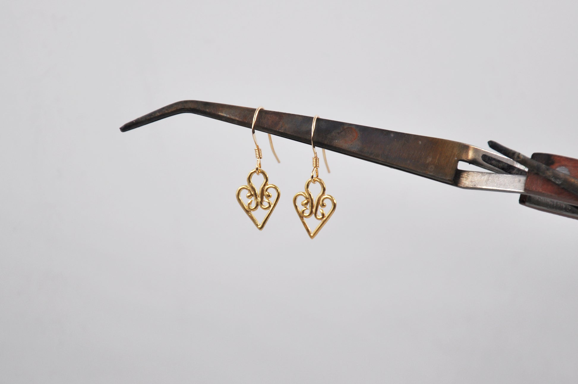 Gold heart-shaped earrings on a gray background