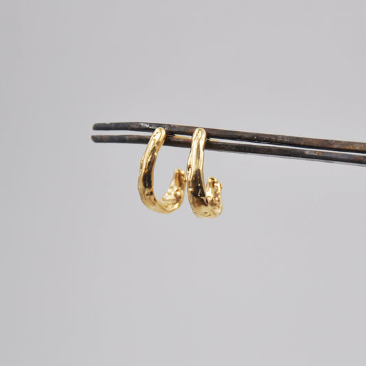 Gold hoop earrings on a gray background