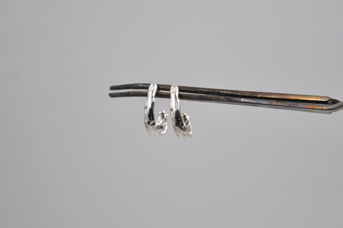 Pair of silver earrings on a gray background