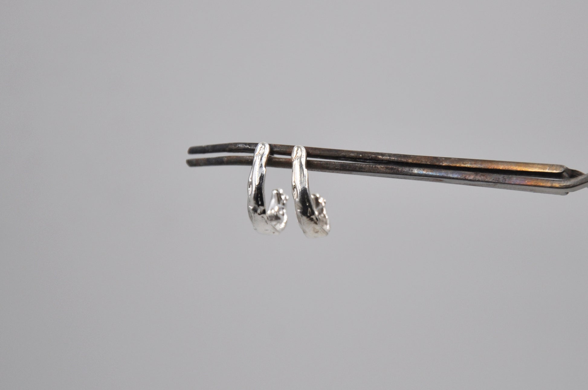Pair of silver earrings on a gray background