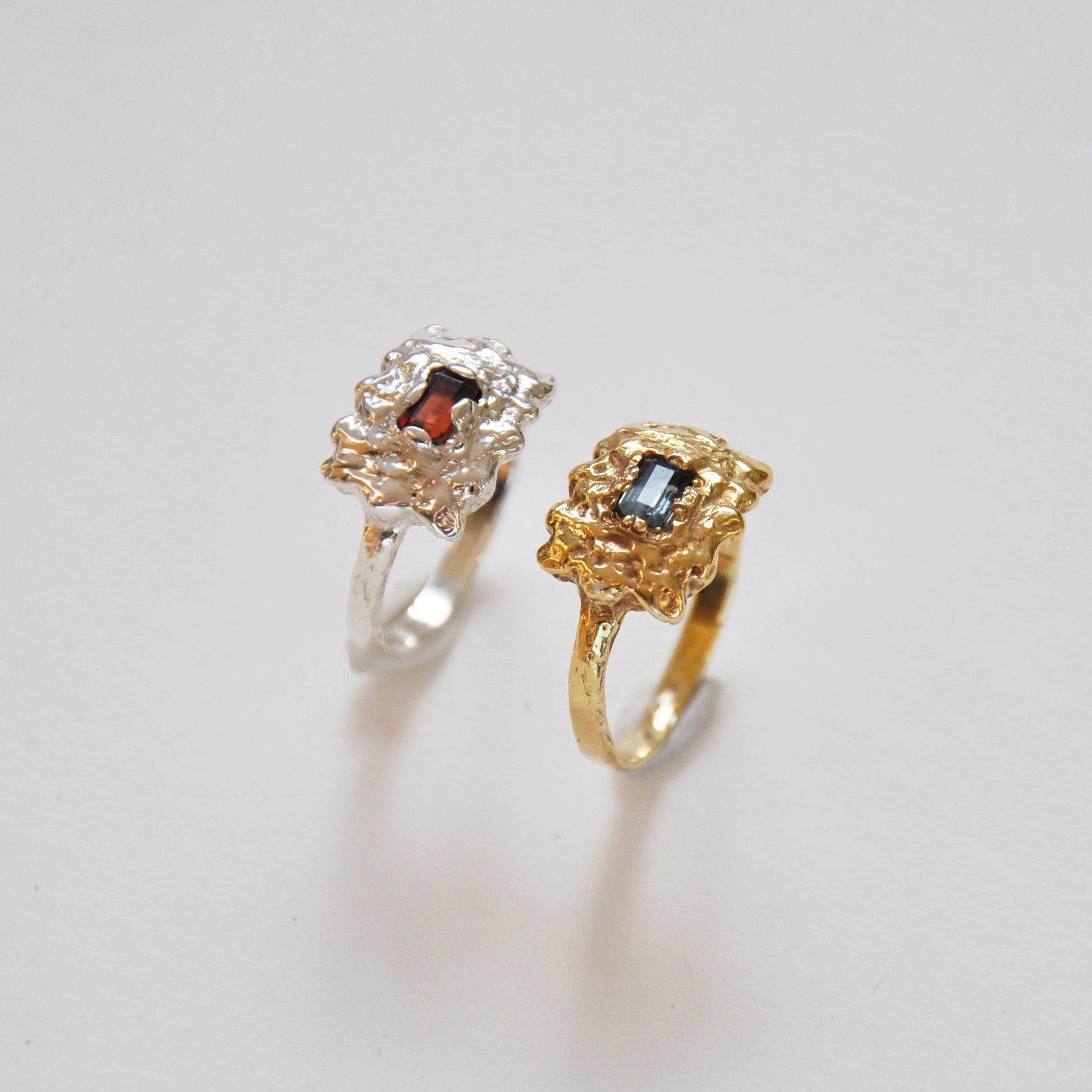 Two rings, one gold and one silver, on a light gray background