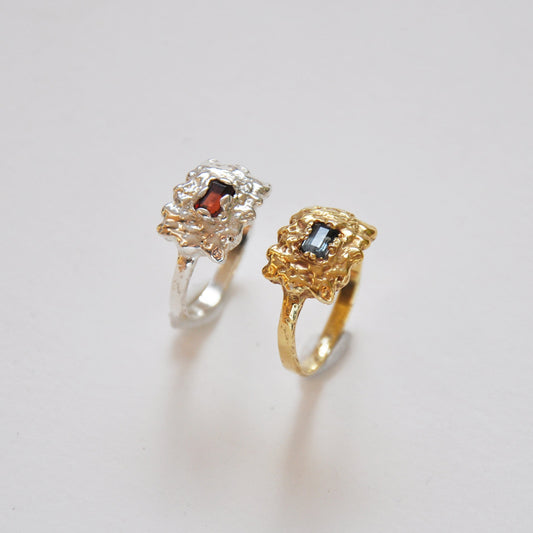 Two rings, one gold and one silver, on a light gray background